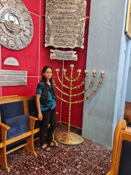 מירה המדריכה ליד החנוכייה בבית הכנסת